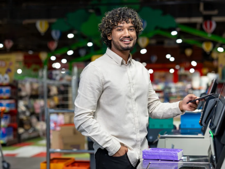 smiling-man-using-smartphone-at-a-self-checkout-in-2026-03-05-11-24-34-utc